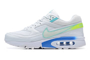 Side profile of a white Nike Air Max sneaker with turquoise and lime-green details and a visible air unit.