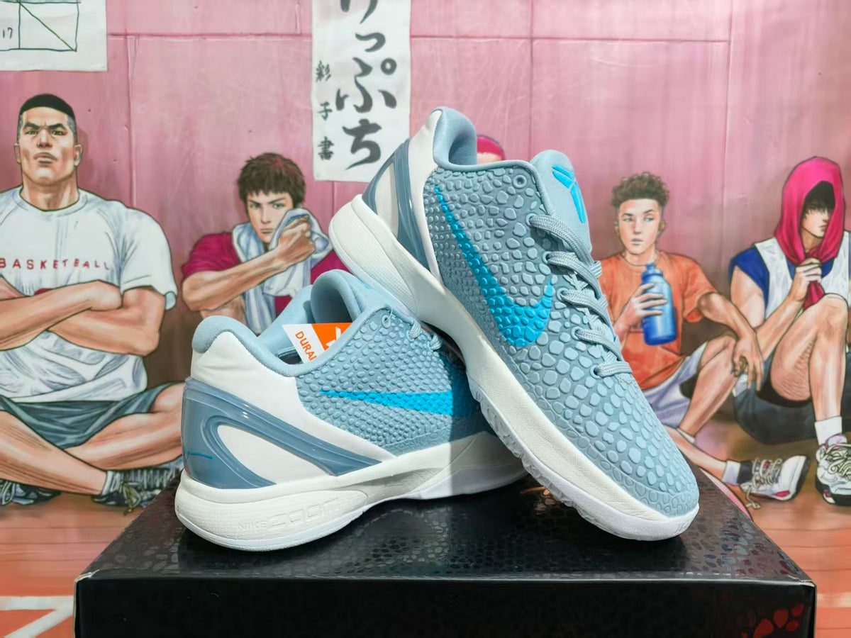 Pair of light blue, white and gray Nike basketball sneakers shown from an angled side view on a black box.