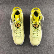 Top-down view of the pair showing pale yellow uppers, yellow collars, light laces, and patterned tongue graphics.