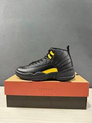 Side profile of a black and yellow Jordan Air Jordan 12 Retro high-top sneaker on a Jordan shoebox.