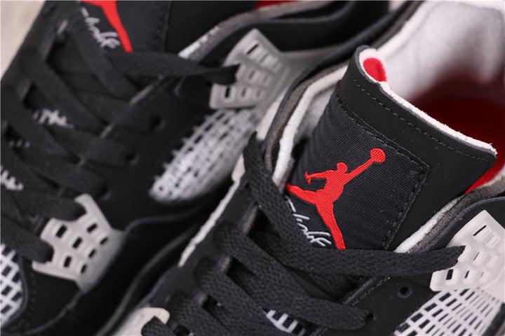 Close-up of black Jordan sneakers showing red tongue branding, black laces, and translucent lace-support hardware.