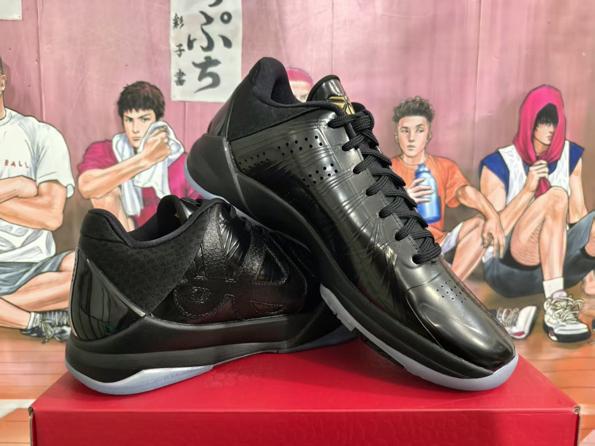 Pair of black low-top sneakers shown from a three-quarter angle on a red shoebox.