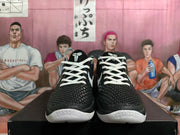 Front view of a pair of black basketball shoes with white laces and textured uppers.