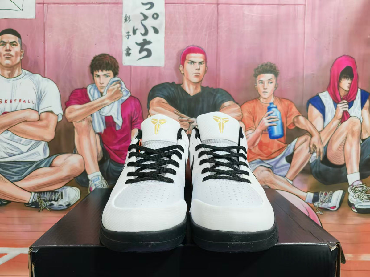 Front view of white and black basketball sneakers with black laces and tongue logos, displayed on a black box.