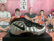 Side profile showing the molded-looking silver upper, black outsole and orange detailing.
