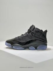 Side profile of a black high-top sneaker with layered lacing, ankle strap, glossy lower panels, and a translucent blue-toned outsole.