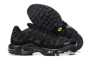 Side view of black Nike Air Max Plus sneakers with patterned uppers and visible sole cushioning