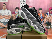 Angled view of two black Nike sneakers displaying the patterned side panels, rounded midsole details, and green outsole.