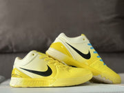 Angled side view of the pair with yellow uppers, cream collars, black Swooshes, and heel graphics.