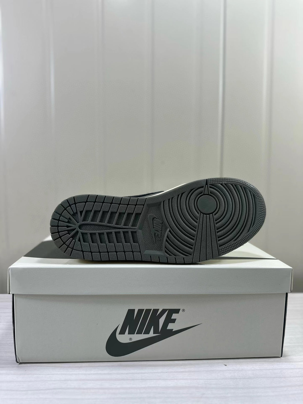 Dark outsole with circular tread pattern displayed on a shoe box.