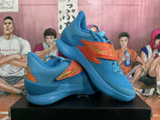 Angled view of the blue sneaker pair highlighting the orange patterned side panels, raised collars, and blue soles.