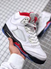 Angled front-side view showing the white toe box, perforated side panel, red accents, black midsole, and blue outsole.