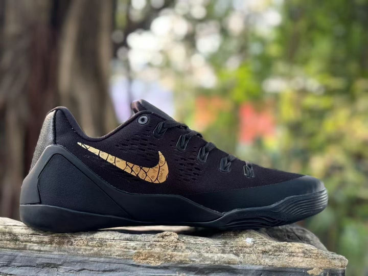 Side view of a black Nike Kobe 9 shoe with a gold-toned scale-pattern Swoosh.
