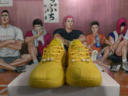 Front view of yellow basketball sneakers showing the laces, white lace beads, and textured toe boxes.