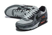 Close view of the grey and black Nike Air Max 90 sneakers with mesh panels, layered overlays, and lace-up fronts.