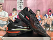 Angled view of the pair showing black textured uppers, red side accents, GT branding, and layered black and red midsoles.