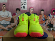 Front view of neon yellow ASICS basketball sneakers with red toe outsole sections.