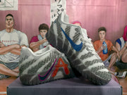 Side view of white and gray Nike basketball sneakers with blue and magenta Swoosh details, textured uppers, and dark patterned soles.