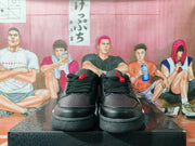 Front view of black low-top sneakers showing perforated toe panels, black laces, and red tongue details.