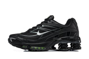 Side view of a black Nike Shox Ride 2 sneaker with silver-toned detailing and green accents.