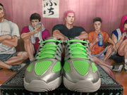 Front view of Nike sneakers showing neon green mesh panels and laces with silver-gray overlays.