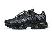 Side view of a black and grey Nike Air Max Plus sneaker with cord-style laces and visible cushioning units.