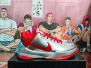 Side profile showing the silver and red colorway, side swoosh, perforated upper, and textured outsole.