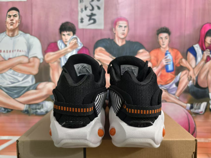 Rear view of black Nike sneakers with orange-and-black heel details and white outsoles.