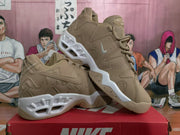 Angled view of two khaki Nike sneakers displaying the side panels, Swoosh logos and contrasting white soles.