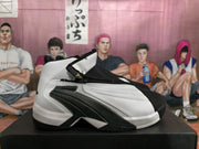 Side view of one white and black high-top sneaker showing the zippered upper and layered black side structure.