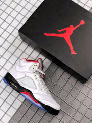 Air Jordan 5 sneaker beside a black Jordan shoe box, showing the white upper, black midsole, red accents, and translucent blue outsole.