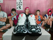Front view of white and black Nike basketball sneakers with patterned uppers, white laces, and red tongue logos.