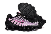 Side and outsole views of black and pale pink Nike Shox TL sneakers.