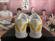 Rear view showing yellow heel panels, vertical heel detailing, and embossed heel emblems on the white basketball sneakers.