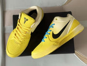 Top and angled view showing the yellow perforated toe, cream collar, black Swoosh, and contrasting blue laces.