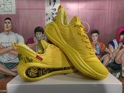 Angled view of the yellow sneaker pair highlighting the padded collars, lace-up construction, red side tags, and sculpted soles.