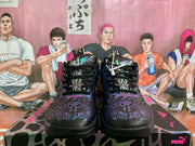 Front view of black Puma sneakers with blue and purple graphic detailing, black laces, and purple artwork on the tongues.