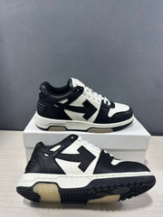 Angled view showing the black-and-white low-top sneakers, side arrow motif, layered sole and outsole tread.
