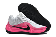 Side view of the white and pink sneaker beside its black outsole, showing the wavy tread pattern.
