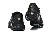 Rear and outsole views of black Nike Air Max Plus sneakers, showing heel cushioning units and small yellow heel details.