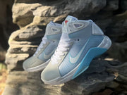 Angled view of the sneakers showing the mesh tongue, lace system, side Swoosh, and blue midsole accent.