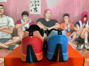 Rear view of the mismatched sneakers, showing contrasting blue and red-orange heel sections and black heel details.