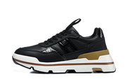 Side profile of a black sneaker with glossy side panels, tan heel accent, and layered white sole.