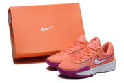 Coral Nike sneaker pair displayed beside an orange Nike shoebox.