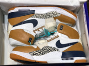 Pair of the sneakers arranged inside an open shoe box, showing the white, tan, navy, and elephant-print color scheme.