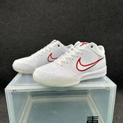 Pair of white low-top basketball sneakers with red branding and perforated toe panels.