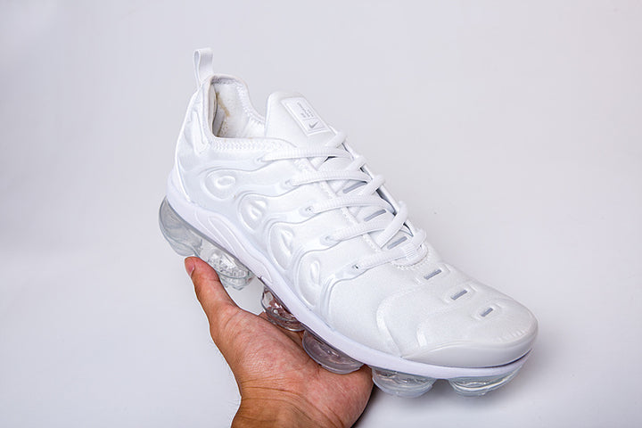 Single white Nike TN-2 sneaker held at an angle, showing the laces and clear segmented sole.
