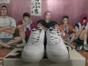 Front view of the white sneakers showing white laces, perforated toe boxes, black Nike logos, and black padded collars.