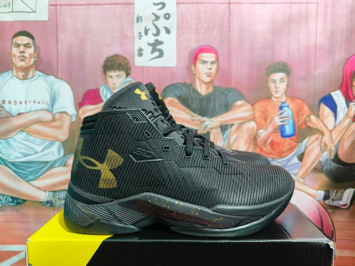 Side view of black high-top basketball sneakers with gold Under Armour branding and a patterned midsole.