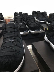Multiple black high-top sneakers displayed on black shoeboxes, showing white midsoles and gold accents.